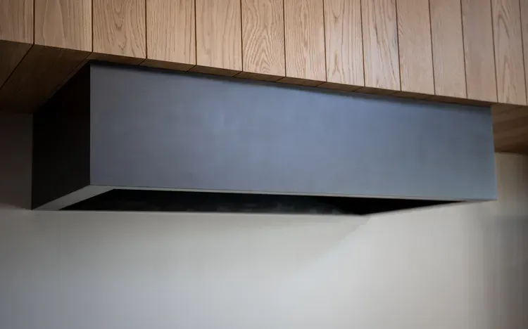 Modern black range hood mounted under wood-paneled cabinetry — Spark Appliance Repair, Mountain View CA